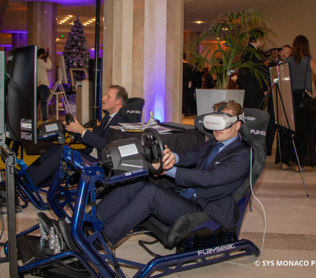 A Sim Racing simulator is being used by two people in the Racing Stand at a corporate event. Un simulateur de course est utilisé par deux personnes dans le stand de course lors d'un événement d'entreprise.